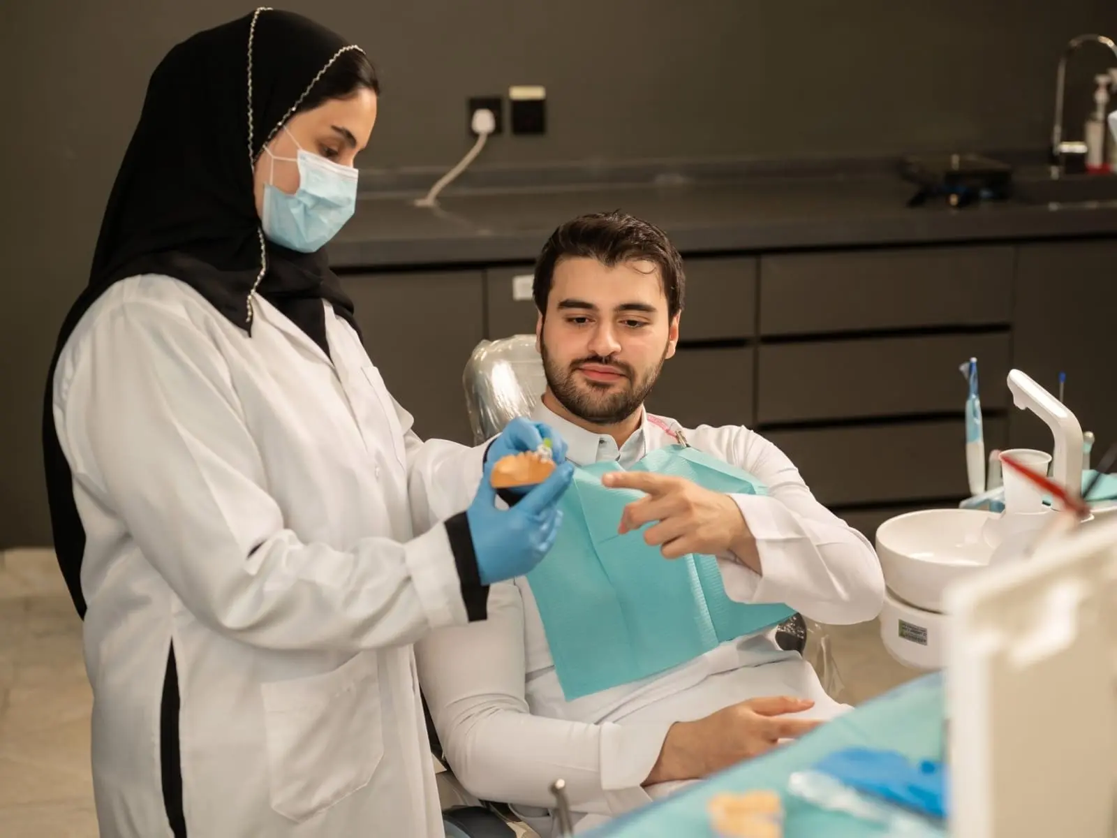 A dentist showing a dental model to a patient in a clinic