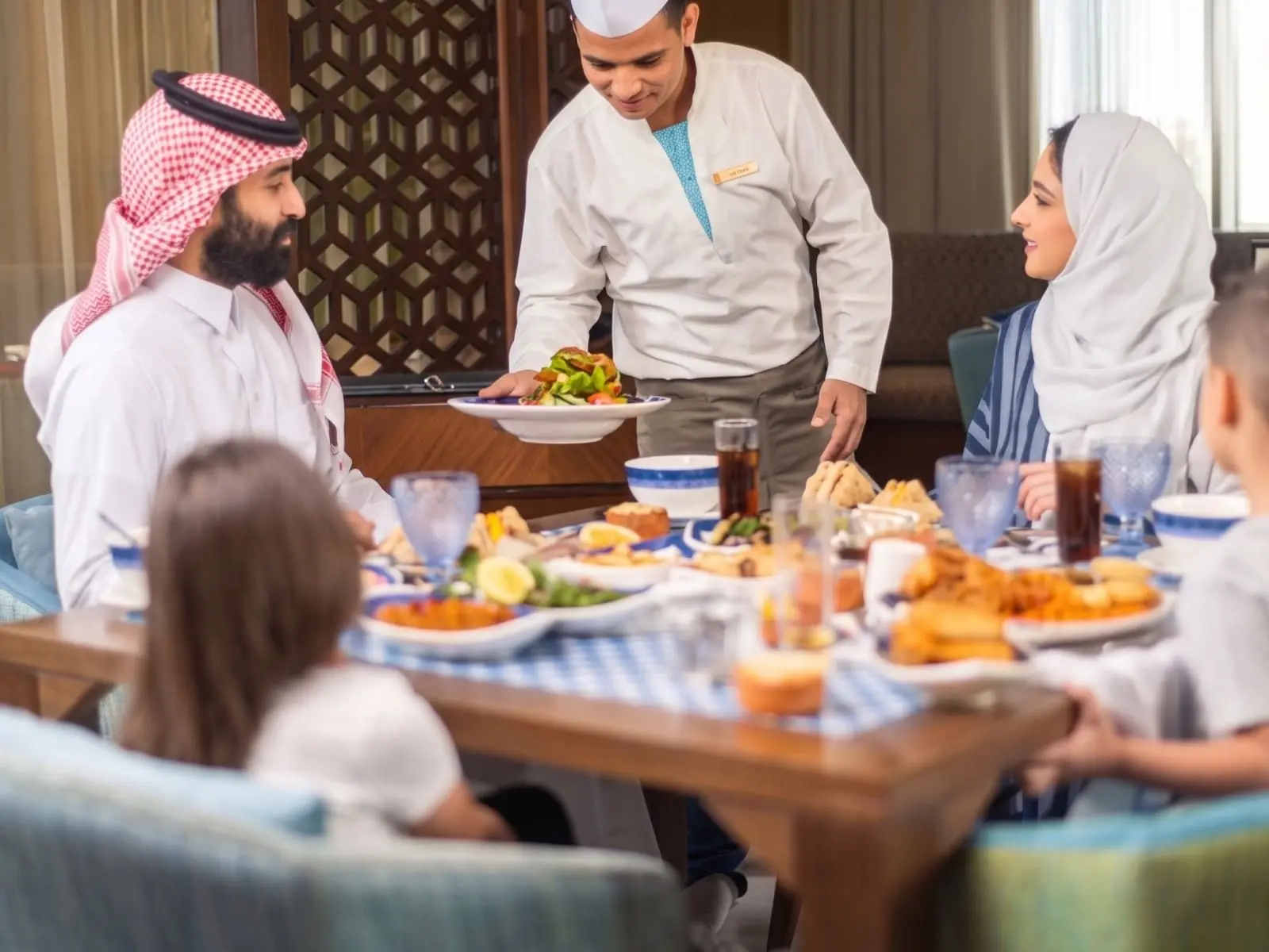 A waiter serving a family a meal at a restaurant table